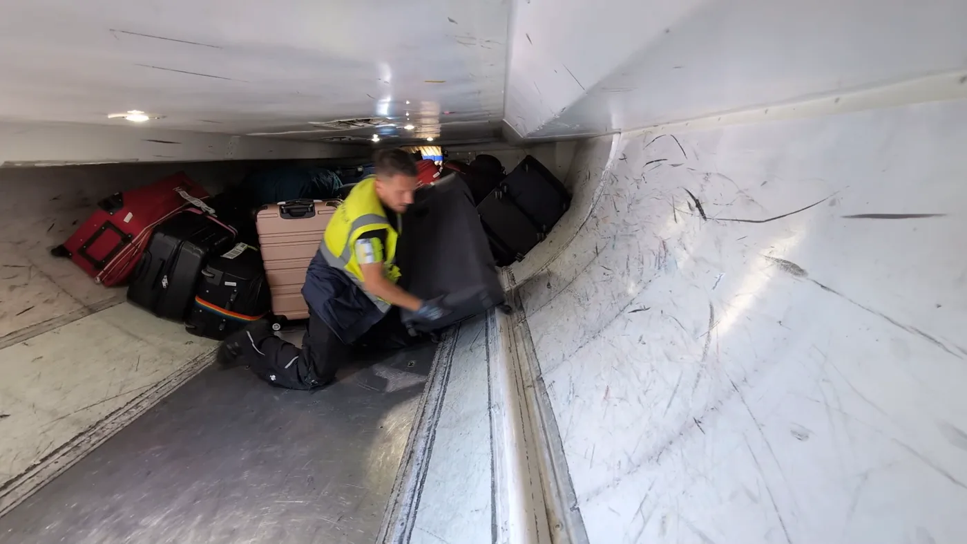 Worker loading baggage manually inside an aircraft cargo hold